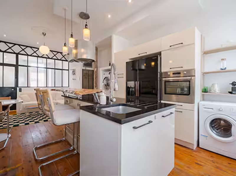 Cuisine équipée moderne avec îlot central, parquet bois et électroménager inox — exemple d'intérieur de particulier entretenu par niiickel à Toulouse-Ouest